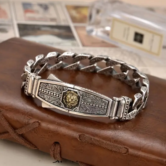 NEMEAN Lion Head Bracelet displayed on leather surface, showcasing silver and gold-tone finish with intricate detailing