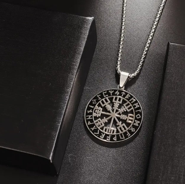 VEGVISIR Norse Compass Pendant Necklace with Viking rune medallion displayed on dark textured surface, showcasing polished stainless steel and intricate Nordic design